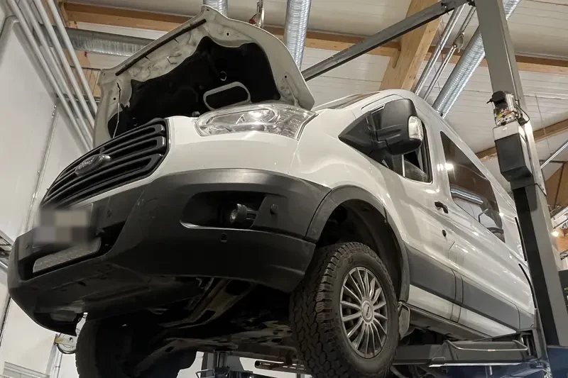 Pakettiauto nostimella konepelti avattuna korjaamolla